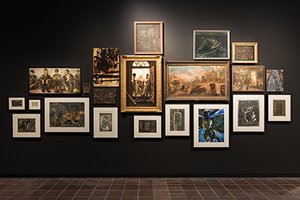 Eine Galerieansicht verschiedener Gemälde mit bergbaulichen Motiven auf schwarzer Wand